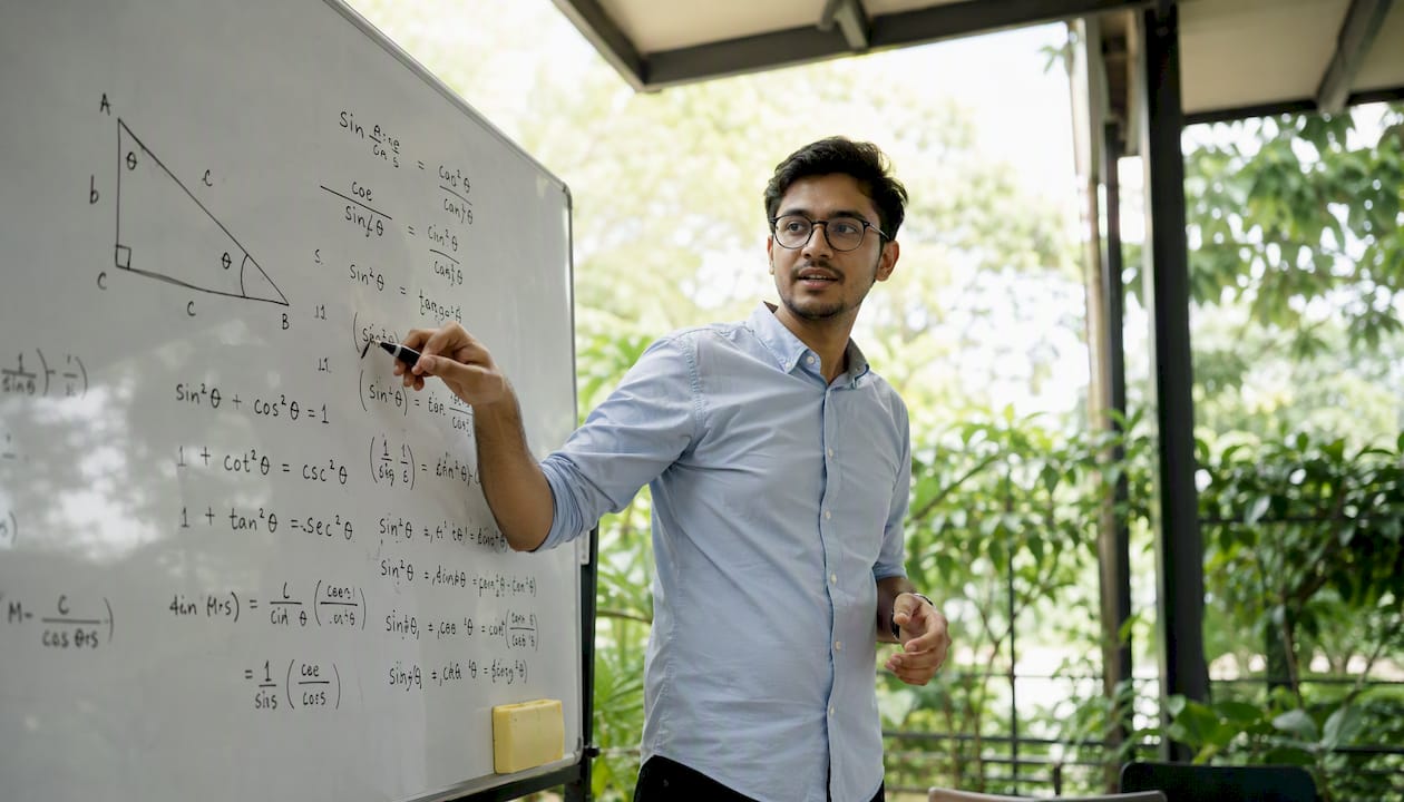 Tutor explaining trigonometric proofs on whiteboard
